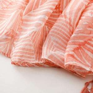 Detailed macro view of bohemian scarf fabric with orange leaf pattern and fringe edges