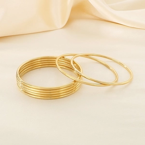 Detailed view of 7-piece 18k gold plated stainless steel bangles on silk fabric