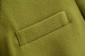 Dettaglio della patta della tasca del cappotto di lana verde con trama del tessuto di qualità