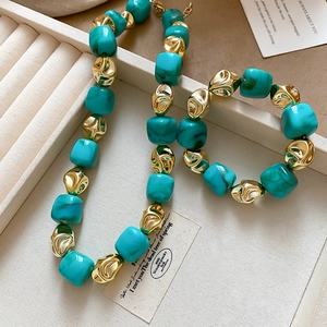 Detailed close-up of marble textured turquoise beads and gold metal links on a display tray