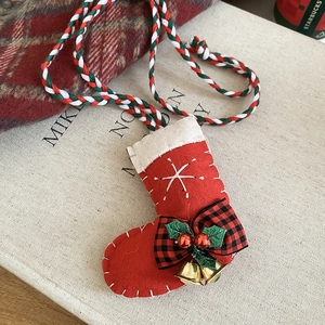 Close-up of a festive Christmas stocking pendant with a red bow and golden bells