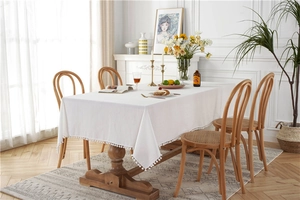 Detail of white cotton tablecloth edge featuring decorative soft pom pom fringe accents