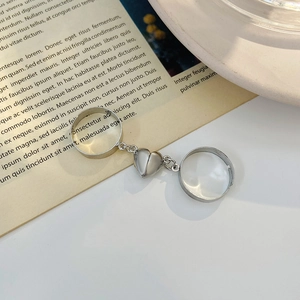 Vue détaillée des bagues cœur magnétiques argentées pour couples sur un fond de livre épuré