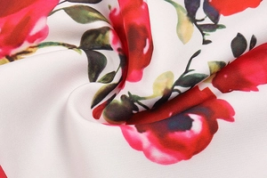 Gros plan sur un tissu en satin soyeux avec imprimé floral de roses rouges sur fond blanc