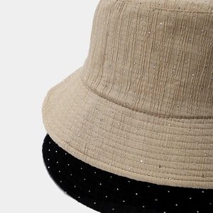 Close-up of pleated bucket hats with sparkling rhinestone details in beige and black colors