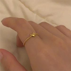 Close-up of minimalist gold twisted rope ring with a 3D heart on the index finger