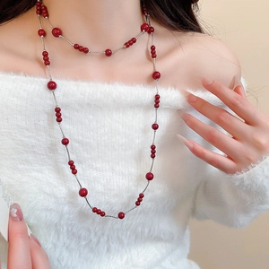 Close-up of elegant long layered necklace with glossy red faux pearls on a silver chain