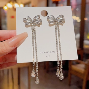 Close-up of silver zircon bow earrings with long tassels and crystal teardrops