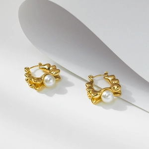 Detailed view of vintage gold hoop earrings featuring a central white pearl and wavy texture