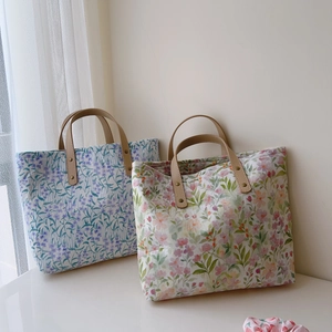 Détail de cabas en coton fleuri avec poignées en cuir renforcées et coutures à rivets