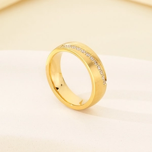 Detailed close-up of golden four-prong eternity ring with diamonds on stone surface