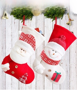 Detail of large knitted Christmas stockings with Santa and Snowman hanging on a wooden wall