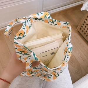 Détail montrant la grande capacité du sac en toile fleurie contenant plusieurs livres épais