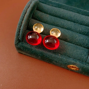 Detailed close-up of resin gourd stud earrings in a green velvet jewelry gift box