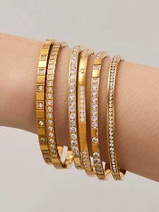 Dettaglio di sei bracciali rigidi geometrici placcati in oro 18k con zirconi al polso