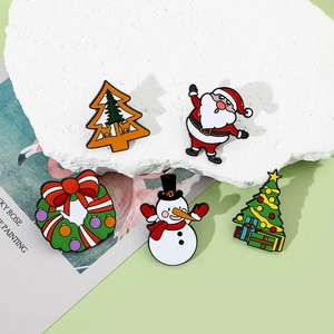 Close-up of five colorful Christmas enamel pins featuring Santa, snowman and Xmas tree