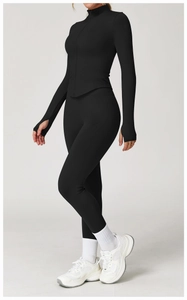 Détail de la veste de yoga noire avec col montant, zip et poignets passe-pouce