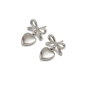 Gros plan de boucles d'oreilles nœud argentées avec pendentifs cœur en acier poli