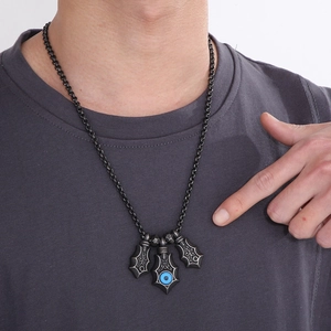 Detail of retro devil eye shield pendants on a titanium steel necklace worn by a male model