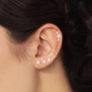 Close-up of S925 silver ear piercing with flower cluster diamonds and gold beads