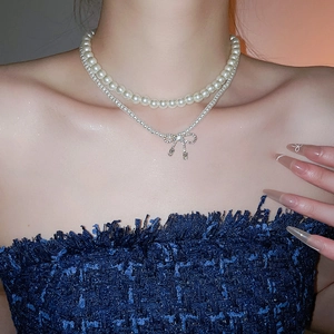 Detail of layered pearl necklace with zircon bow pendant on model's neck