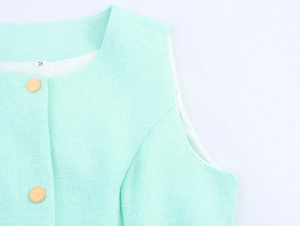 Détail du gilet en tweed vert menthe avec boutons dorés et col rond élégant