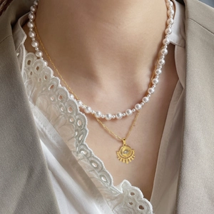 Détail du collier à deux rangs en or 18 carats avec perles et pendentif oeil sur un mannequin