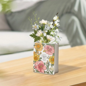Detail of book-shaped ceramic vase with vintage floral print and decorative English text