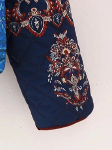Detailed macro view of quilted navy sleeve featuring vintage floral paisley patterns