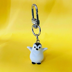 Cute 3D resin penguin keychain with silver lobster clasp on a bright yellow background