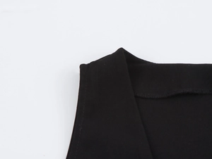 Close-up of sleeveless jumpsuit neckline and shoulder texture in black woven fabric