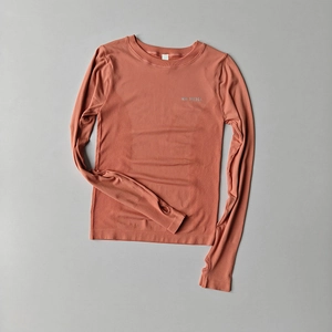 Detail of seamless yoga top featuring thumbholes and breathable texture in burnt orange