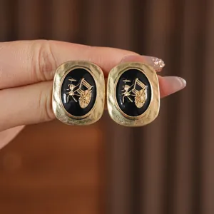 Vintage gold oval earrings with black enamel and rickshaw relief detail