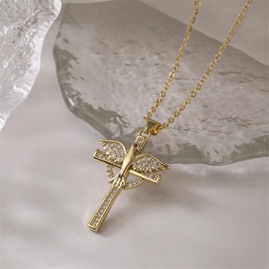 Makroaufnahme: Goldener Flügel-Kreuz-Anhänger mit rotem Edelstein auf Eiskristallen
