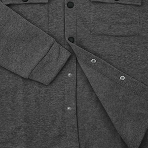 Detail of dark grey knit jacket showing snap buttons and texture on chest pockets