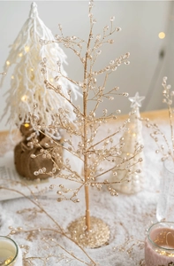 Detail of a golden glitter Christmas tree decoration with clear waterdrop beads and warm lights