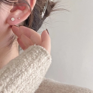 Detail of 925 sterling silver smiley face and ball stud earrings on model's ear