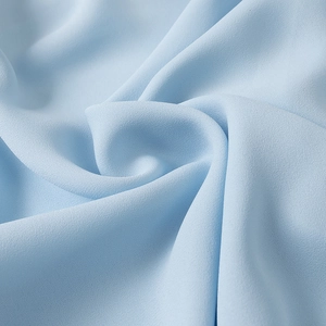 Macro shot of light blue chiffon fabric texture with soft ripples and subtle grainy finish