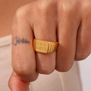 Detailansicht eines goldenen quadratischen Siegelrings mit Gravur an einer Hand
