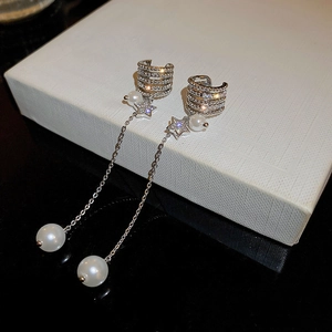 Detail view of silver tassel earrings with white pearls and sparkling star elements
