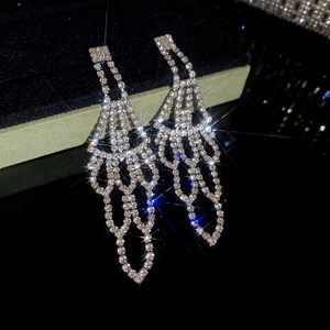 Macro shot of silver tassel earrings with sparkling rhinestones on a dark surface
