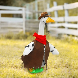 Detail of goose plush toy in western cowboy outfit with hat and scarf on farm