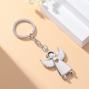 Detailed view of a silver metal angel keychain with heart cutout on a soft white podium
