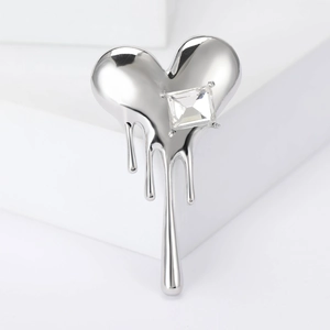 Macro detail of silver fluid molten heart brooch with a sparkling square cut zircon stone