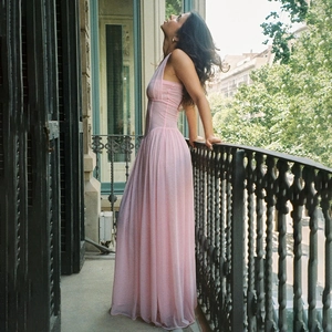 Elegant pink halter maxi dress in pleated chiffon, shown on an classic balcony setting