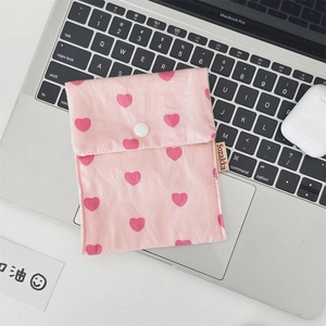 Close-up of pink heart-patterned cotton pouch with snap button on a laptop keyboard