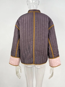 Rear view of a vertical quilted women's jacket with contrast trim and pink cuffs