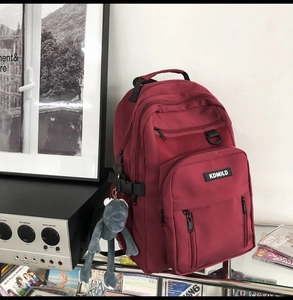 Dettaglio di uno zaino scolastico bordeaux con tasche multiple a cerniera capienti