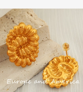 Macro shot of vintage golden titanium steel twisted earrings on a light stone base