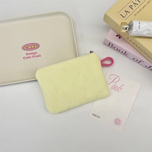 Macro view of a light yellow quilted coin purse with zipper and pink ring handle